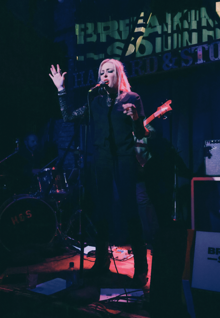 Female performer at standing on stage with microphone. photo credit americangothicrock.com 